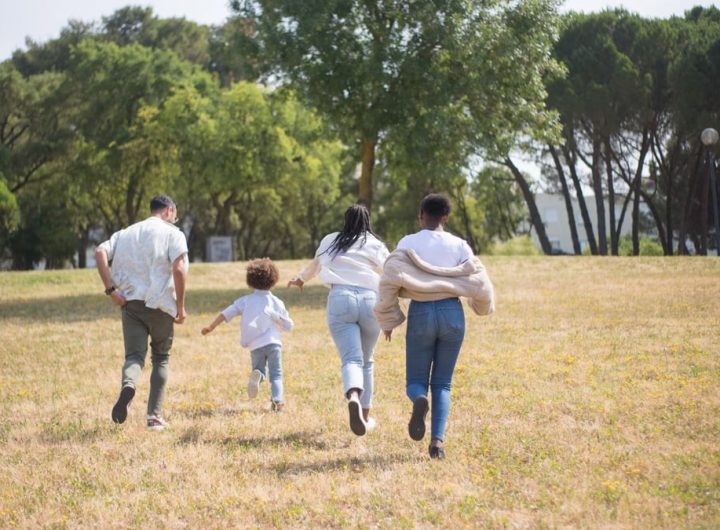 Cheerful family walking together in a sunny park surrounded by trees.